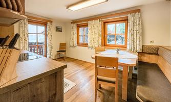 A cozy kitchen with bright windows and a dining table. The warm wood tones create an inviting atmosphere.
