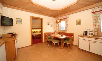 An inviting interior with a dining area and a small kitchen. The walls are decorated with light colors and loving details.