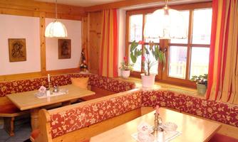 A cozy room with wood paneling and red patterned benches. Large windows let in plenty of light and create an inviting atmosphere.