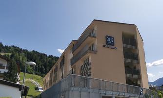 A modern building named "3UE" stands in a picturesque mountain landscape. The architecture is simple and invites you to linger.