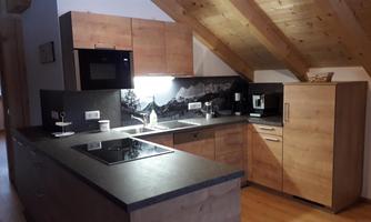 A modern kitchen with wooden cabinets and an elegant countertop. The slanted ceilings give the room a cozy atmosphere.