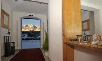 An inviting entrance area with a red carpet and wood paneling. Snow-covered mountains are visible in the background.