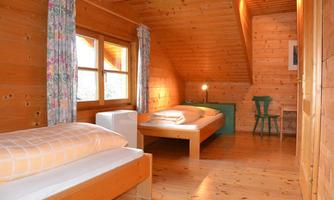 A cozy room with wooden paneling and two beds. Light streams through the window, creating an inviting atmosphere.