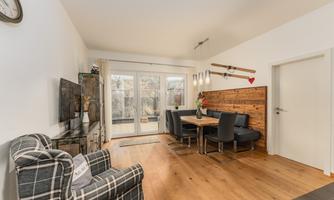 A cozy living space with a dining table and chairs. Large windows let in plenty of daylight and offer a view outside.