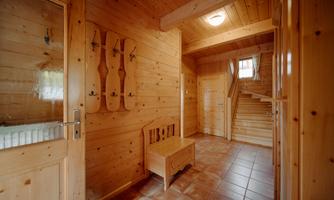 A cozy hallway with wooden paneling and a tiled floor. A bench and wall hooks complete the inviting impression.