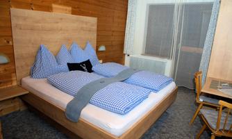 A cozy bedroom with a large bed and checkered bedspreads. The wood paneling and wooden furniture create a warm atmosphere.