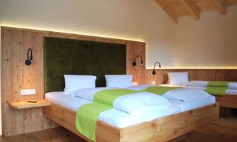 A modern bedroom with wooden details and a cozy atmosphere. The bed has white bedding and green accents.