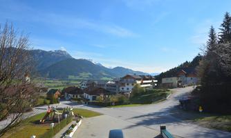 A peaceful landscape with a small village and mountains in the background. The sky is clear and blue, ideal for a relaxing day in nature.