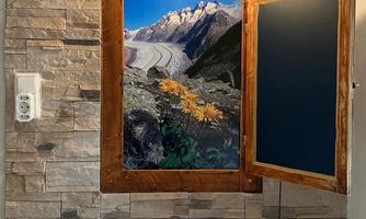 A modern bathroom with an elegant washbasin. In the background, there is a photo of mountains and flowers in a rustic wooden frame.