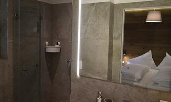 A modern bathroom with natural stone walls and a large mirror. The lighting creates a pleasant atmosphere.