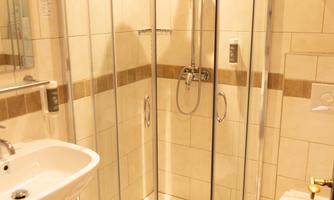 A modern bathroom with a glass shower cubicle and bright tiles. There is a sink and a toilet, which are functionally arranged.
