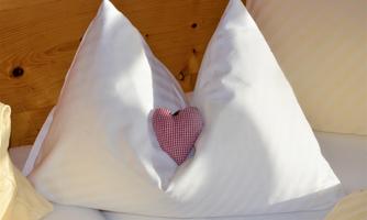 Two pillows shaped like mountains with a red heart in the middle. The pillows are white and create a cozy atmosphere.