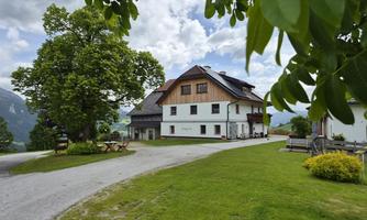 A picturesque building surrounded by green meadows and trees. The sky is cloudy, creating a calm atmosphere.