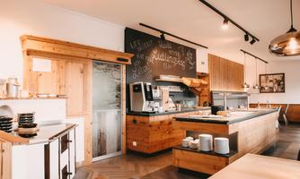 A modern cafeteria with warm wooden elements and a friendly atmosphere. The area is clean and inviting with a counter for food and drinks.