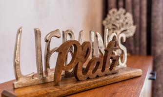 A decorative wooden sign with the inscription "Favorite Spot" in various fonts. It stands on a table against a neutral background.