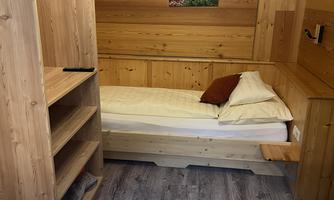 A cozy room with wooden paneling and two beds. A picture of nature hangs on the wall.