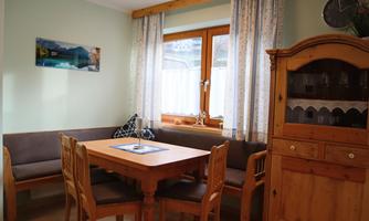 An inviting dining area with a wooden table and chairs. A window with curtains lets in plenty of daylight.