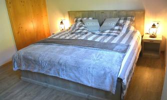 A cozy bedroom with a large bed and stylish nightstands. The warm lights create an inviting atmosphere.