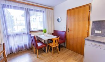 A cozy kitchen area with a table and chairs. Large windows let in plenty of light.