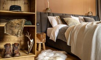 A modern bedroom with a comfortable bed and stylish wooden furniture. Personal details like boots and hats add charm to the space.