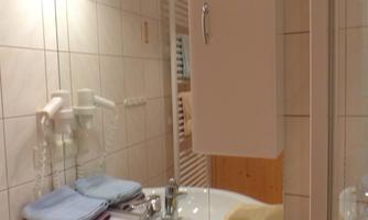 A modern bathroom with a sink and bright tiles. Towels in various colors are neatly placed on the sink.