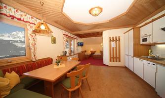 A comfortable kitchenette with wooden cladding and a dining table.  
Plenty of light streams through the windows, which offer a beautiful view of the mountains.