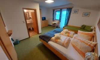 A cozy room with two beds and a small table. There is a television and a window with a view.