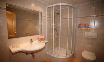 A modern bathroom with a shower, a sink, and a mirror. Towels in bright colors are neatly arranged.