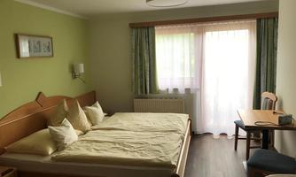 A cozy bedroom with two beds and modern furniture. Large windows provide plenty of natural light and a view outside.