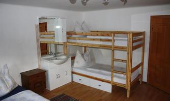 A simple room with a bunk bed and a sink. Wooden cabinets and a carpet complement the furnishings.