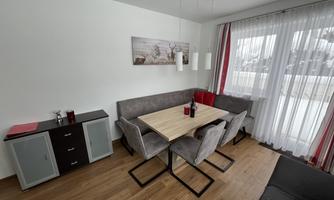 A modern dining room with a large table and cozy chairs. Large windows provide plenty of light and a welcoming atmosphere.