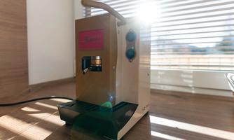 A stylish coffee machine is on a table. The sun is shining through the window and illuminating the device.