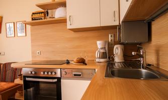 A modern kitchen with wooden shelves and appliances. It includes an oven, a sink, and a coffee machine.