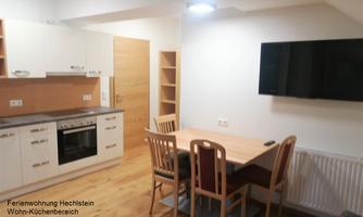 A modern kitchen with a dining area and a television. The decor is bright and cheerful.