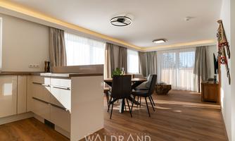 A bright, modern kitchen with an open living area.  
Large windows provide plenty of daylight and an inviting atmosphere.