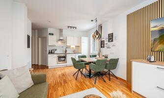A modern apartment with an open living and dining area. It features a bright kitchen and stylish furniture.