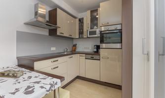 A modern kitchen with bright cabinets and functional equipment. In the foreground, there is a table with a decorative tablecloth.