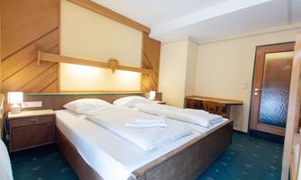 A cozy bedroom with a large double bed and two nightstands. The room has warm wooden decor and plenty of space.
