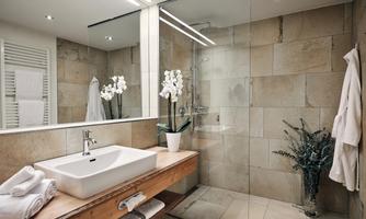 A modern bathroom with a glass shower and an elegant wooden shelf. White towels and orchids create a stylish atmosphere.