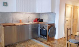 A modern kitchen with stainless steel appliances and wooden countertops. The floor is made of wood and there is a bright, friendly atmosphere.