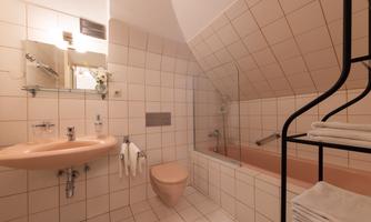 A bathroom with bright tiles and a bathtub. It features modern furnishings with a sink and towels.