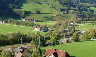 A picturesque landscape with green hills and scattered villages. The nature is lush and a tranquil river flows through the storybook scenery.