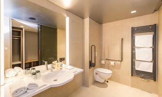 A modern bathroom with a sink and a large mirror. Towels are neatly arranged on a towel rack.