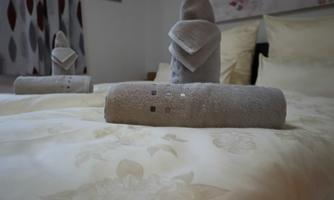 A cozy bedroom with a beautifully decorated bed. Folded towels in soft colors are placed on the bed.