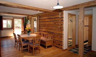 A cozy room with wooden walls and a dining table.  
Plenty of daylight streams through the windows, creating an inviting atmosphere.
