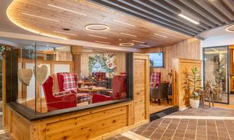 An elegant reception area with wooden elements and modern furniture. Red armchairs and plants create an inviting atmosphere.