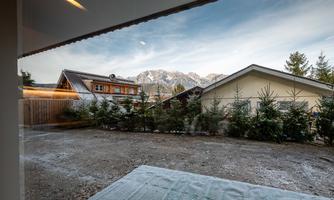 A tranquil landscape with mountains in the background and two houses in the foreground. The sky is clear and showcases the beauty of nature.