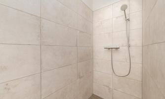 A modern shower with bright tiles and a simple shower fixture. The space feels clean and minimalist.