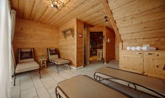 A cozy wellness area with wood paneling and two loungers. The room is bright and invites relaxation.