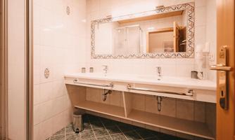 A modern bathroom with a double sink and a large mirror. The walls are tiled and harmoniously blend into the decor.